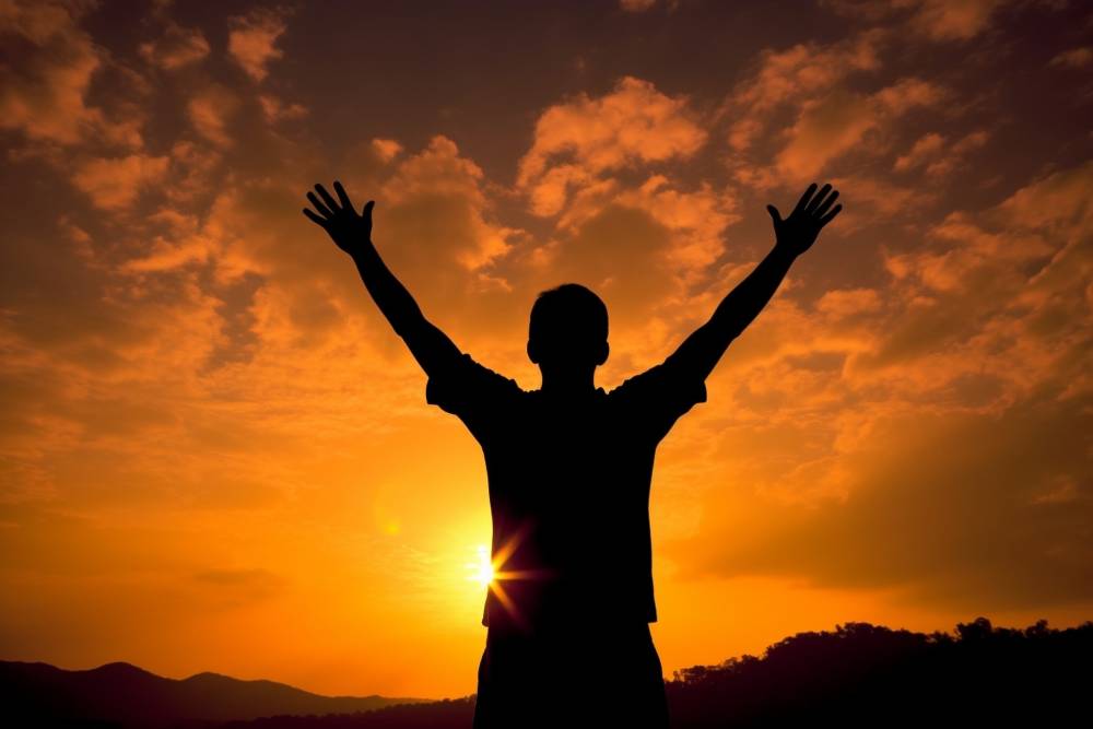 The Condition of Man Silhouette of man in the evening watching beautiful sunset with arms raised up outstretched cheering and happy